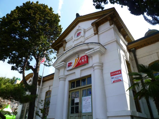 テントと桜と人波であやうく見逃しそうだった<br /><br />《 旧鎮海郵便局 》<br /><br />中原ロータリーの一角に立つ 1912年完成の白と若草色のコントラストが美しいロシア風折衷様式の優美な建物 −−プサンナビより−− <br /><br />日本式家屋が連なる景色も見たかったけど、探せませんでした。<br />なにしろすごい人出です。