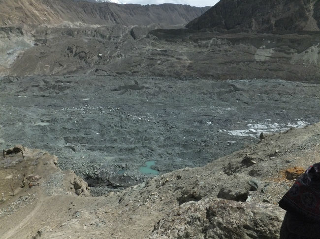 ホーパル氷河を上から眺める。<br /><br />凍土というとシベリアなどの真っ白を想像するけれど、ここは黒い。<br />風で運ばれた砂が上を覆っていて、氷の地面は砂の下にある。<br />おかげで寒そうに見えないが、そこは凍土、奥に座するディラン峰のお陰もあり、晴れていてもやっぱり寒い。<br />