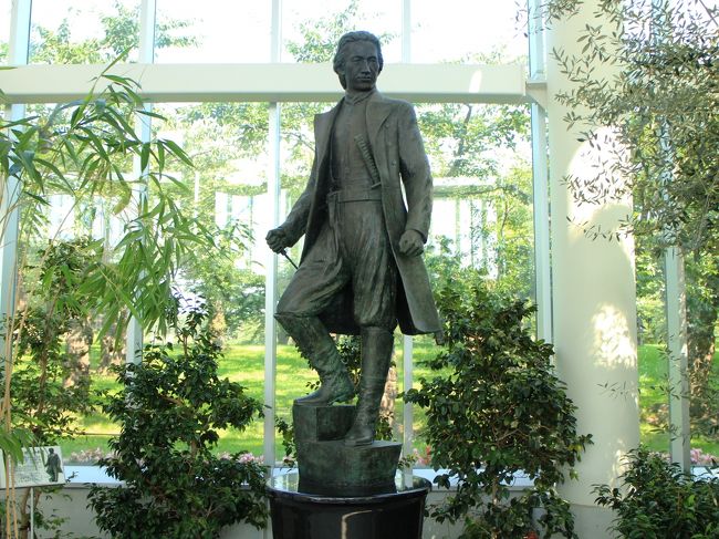 三人目は土方歳三。<br /><br />言わずと知れた、新選組副長です。<br /><br />多摩群の農家の末っ子として生まれましたが、幼い頃から武士になることに強い憧れを抱いていました。<br /><br />１０代半ばから江戸の呉服屋に奉公に出て、その後薬売りの行商をしながら各地の剣術道場で修行を積みました。<br /><br />そして、天然理心流の道場試衛館で近藤勇と運命的な出会いを果たし、道場の仲間らとともに京都へ赴き、浪士組に加わったのでした。<br /><br />浪士組は１４代将軍徳川家茂公の上洛を守護するために結成された組織で、武術に秀でた者であれば犯罪者でも参加することができました。<br /><br />試衛館の仲間たちは芹沢鴨ら水戸浪士の一派と合流し、浪士組の三番隊に編成されました。<br /><br />将軍上洛も無事に終わり、浪士組には帰還命令が出されますが、芹沢・近藤グループはそのまま京都に留まり、京都守護職を務めていた会津藩預かりとなり、壬生浪士組として行動するようになったのでした。<br /><br />これが後の新選組です。<br /><br />なお、芹沢・近藤グループと別れて江戸に帰還した浪士組は、後に新徴組として江戸の警護に当たることになったのでした。<br /><br />その後、リーダーである芹沢鴨の傍若無人の振る舞いに嫌気がさした近藤ら試衛館グループは、芹沢の暗殺を決行。<br /><br />その実行役の中に、土方歳三も含まれていました。<br /><br />そのように京都で暴れまわった土方歳三の像がなぜ置かれているのか。<br /><br />ここ函館は、波乱万丈の生涯を送った彼にとって最後の地だからです。