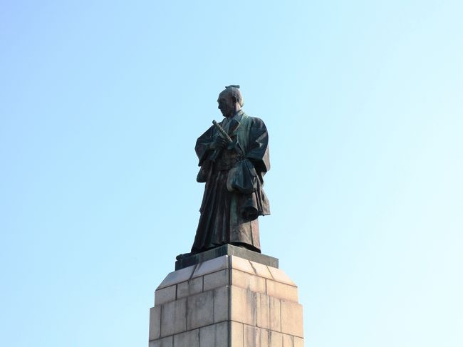 函館護国神社の参道を、宝来町電停に向けて歩きます。<br /><br />参道の入り口には、高田屋嘉兵衛銅像が建てられています。<br /><br />高田屋嘉兵衛は淡路島の貧しい農家に生まれましたが、幼い頃から船に高い関心を持ち、船乗りとして異例の出世を果たしました。<br /><br />２８歳の時に当時最大規模の船を建造し、船持船頭として蝦夷との交易を進め、函館の街の発展や国後・択捉島の開拓にも力を尽くしました。<br /><br />文化８年、ロシアの軍艦ディアナ号の艦長ゴローニンが、７人の船員とともに国後島で幕府の役人に捉えられました。<br /><br />あくる文化９年にはディアナ号副艦長リコルドが、報復するかのように高田屋嘉兵衛らを捉え、カムチャッカへと連行しました。<br /><br />嘉兵衛は幽囚の地で必死にロシア語を習得し、ゴローニンの釈放のために折衝役を果たし、ついに両国は和解するに至ったのでした。<br /><br />この像は箱館開港１００周年を記念し、昭和３３年に建てられたものです。<br />