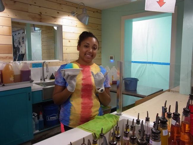 レインボーを注文。店員さんが手際よく作ってくれます。「写真撮ってもいいよ」と言ってくれたのでパチリ＾＾　おねえさんのTシャツとシェイブアイスが見事に同化中。