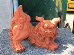 昼食の場所をガイドブックで探していると「嘉とそば」と言う店が美味しいらしいということになり、その店を目指すことに。
しばらく走っていると進行方向右側に看板を見つけ、車を∪ターンして駐車場に入りました。
時間は12時ちょうどくらいで駐車場には4〜5台の車が停まってました。
写真は店の入口の門柱に鎮座していたシーサー君です。素焼きかな?