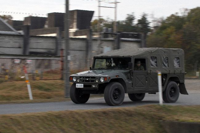 早朝の駐屯地駐車場の横を警備の車が駆け抜ける。