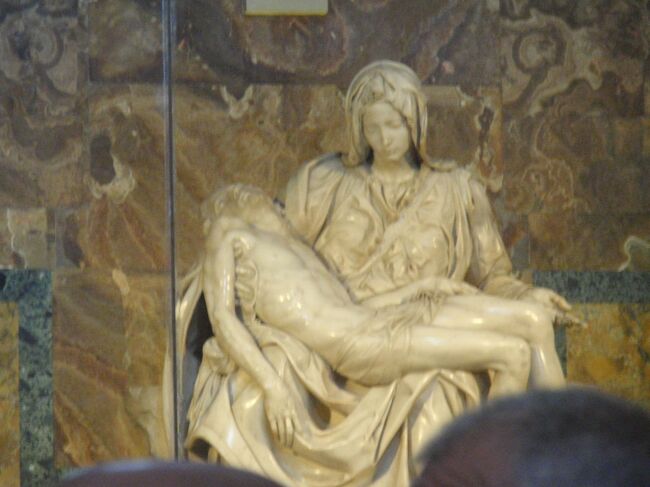 ミケランジェロの作品「ピエタ」。ガラスケースでガードされています。<br />＊ピエタとは、イタリア語で慈悲、敬愛を意味する言葉。十字架から降ろされたイエスの遺体を膝の上に抱いて嘆き悲しむ聖母マリアの姿として表現されている。母親が死んだ我が子を抱くというエピソードが主題。ピエタの主題は、数多くの絵画、彫刻の名作が生まれた。中でも最高傑作は、本作、ミケランジェロのピエタ像である。<br />＊ミケランジェロ２０代前半の作品。