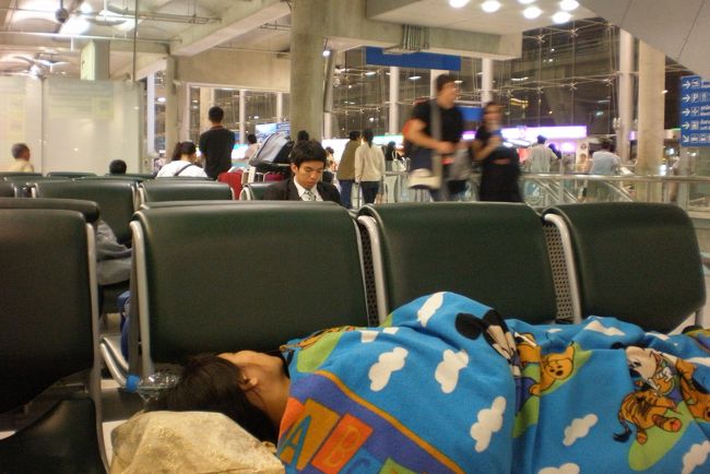 　普通ならば町に出てホテルに泊まり、早朝再び空港に戻って来るか、空港ホテルに泊まるのだろう。<br />　が、私は絶対にそんなことはしない。<br />　空港で仮眠するのだ。<br />　『電波少年』の『猿岩石・アジア無銭旅行』に憧れて海外旅行を始めた私には、そんな贅沢なことは許されない。<br />　快適さをお金で買おうとするのは堕落でしかない。<br />　見ろ。<br />　あんなに若い女の娘だってバックを抱えて寝ているではないか。　　<br />　と粋がってはみるが雑音と明日への不安で熟睡できない。<br />　うとうとするとすぐに目が覚めてしまう。<br />　目の前のベンチでは、タイ人の若い女性が毛布をかぶって気持ち良さそうに眠っている。<br />　なんと逞しいこと。