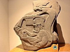 そしてラ・ベンタ遺跡からでたこの石板が、また面白い。
ラ・ベンタ遺跡公園に置いてあるのはレプリカで、本物の石板はメキシコ・シティの考古学博物館に展示されているのだが、この石板が表すものは、王族が神の化身である蛇を纏う姿だと云われている。

でも、それだけではない。
この先に記す説は信憑性には欠けるが、ある著名な作家によれば、この石版は宇宙船の様な機械を操作する王の姿を表している…らしい。

その作家の説によると…
トランシーバーの様な通信装置を頭に付けた男が、左手でサイドブレーキの様なレバーを操作し、右手には機械を持ち、更にその腰にはシートベルトを締めている…そうだ。
頭の上にある四角い箱はこの乗り物のコントロールボックス…と書いてあった気がする。

まあ、見方によっては見えないこともないかな。

（写真：メキシコ・シティの国立人類学博物館で撮影）