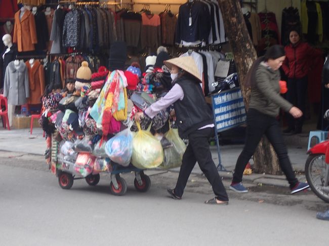 まずは、ハンダォ通りで、<br />ノン（女性用ベトナム三角帽）を被って<br />ものを売っている女性を。