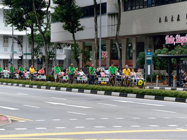 シンガポール名物のトライショーが観光客を乗せて列をなして進んできます。<br />トライショーは、サイドカーをつけた自転車です。