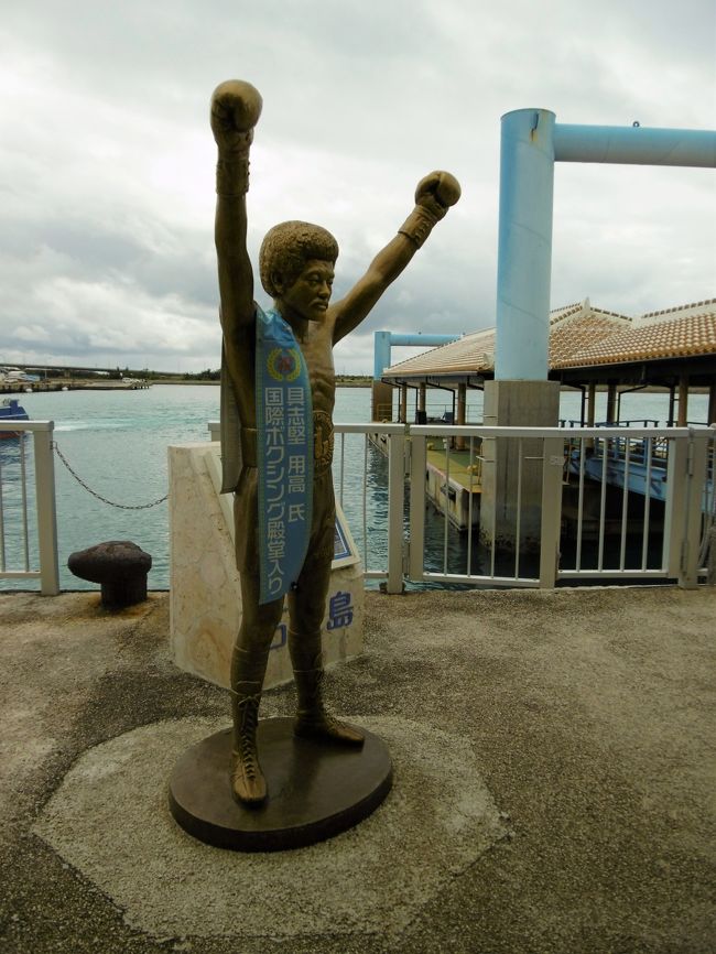 ３度目にして、やっと目撃した「具志堅用高」像。<br />フェリー乗り場近くにあるが、かなり小さいので、今まで見落としていたのだった。<br />逆光だったので、あまりよく写っていないのが残念。<br /><br />いろいろな人が、記念撮影していた。