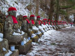 今宵の宿は湯元温泉なのだが、憾満ヶ淵のキャンドルページェントなるイベントと花火を撮影すべく、一旦いろは坂を下り、田母沢御用邸記念公園の駐車場に車を入れ、歩いて憾満ヶ淵へ。
ずらりと並んだ憾満ヶ淵の並び地蔵。ここも雪が少ない。真っ白な雪の中にお地蔵さんたちの赤い帽子とよだれかけが並ぶとフォトジェニックなのだが、道の雪は半分融けている。