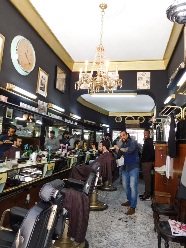 シャトルバスでレスタウラドーレス広場で下車。１１時頃のバスでしたが、乗客は私を含めて５人だけでした。宿に荷物を預けてから、早速リスボンの街歩きを開始します。見たいところがたくさんあるのに、時間がなさすぎて、リスボンでまとまった時間が取れるのは、今日の午後だけです。<br />あとは少しの時間を利用して、ちょこちょこ見ようと思っています。<br /><br />写真はロシオ広場近くの散髪屋さん。ちょっと立ち止まって見ただけですが、こちらを向いている手前のお兄さんが店の外まで出てきてくれて、行き過ぎる私を呼び止めて、「見ていけ、写真撮って行け！」（というような事を言ってくれてたと思う）と言って、わざわざポーズを取ってくれました。うわぁ、フレンドリーだなぁ、これがポルトガルの第一印象でした。