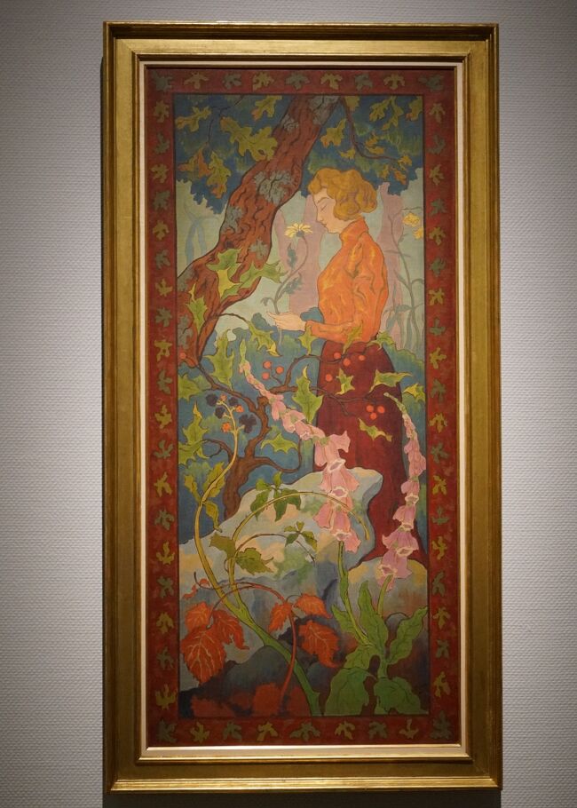 ポール・ランソン「ジギタリス 」1899年<br />19世紀末のナビ派の一員として活躍したランソンは、同僚のドニやボナール、ヴュイヤールと同様、装飾的な画面を得意としました。タイトルのジギタリスとは、前景右手に伸びる釣鐘状のたくさんの薄紫の花をつけた植物です。掛け軸にも似た縦長の画面に描かれたこの作品は、いわゆる当時の日本趣味（ジャポニスム）を反映していますが、同時に、装飾性・平面性など、画面の二次元的特性を重視したナビ派の造形原理に基づいています。実現はされなかったもののタピスリー（綴れ織）のための下絵として制作されたという経緯からみても、中世の「花散らし紋様（ミルフルール）」のタピスリーを強く意識して作画されていることは明らかです、また、曲線を多用した表現は、アール・ヌーヴォーの工芸に直結しています。