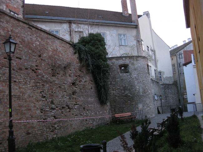 城壁は建物に取り込まれ、外側は民家が密集。わずかに空いた隙間をすり抜けるようにして遊歩道が造られている。<br />