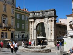 セルギウスの凱旋門です。(セルギ門）
ローマ帝国に功績があったセルギウス家の人々を讃えるために紀元前２７年に当時の城門前に建設された凱旋門です。
両方の門をくぐると当時のメイン・ストリート、デクマヌス大通りへと続いていました。
城壁はその後取り壊され、現在は繁華街の真ん中に２千年以上も前の門が建っているんです。
Trg Portarataはセルギウスの凱旋門の前の小広場。いぜんはここに城門がありました。ここはセルギ通りとGiardini通りが交わる所です｡