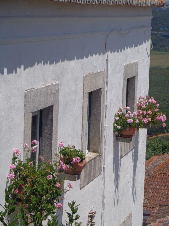民家の窓には色とりどりの花が飾られている