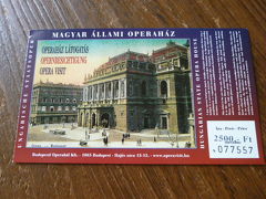 　私はヨーロッパ（特に東のほうのヨーロッパ）好きでありながら、クラシック音楽にもオペラにも興味が殆どない人間です。どのくらい興味がないかというと、以前音楽の都ウィーンに行ったときもオペラ座では写真を撮っただけ、というくらい興味がありません。

　でも今回は見ておきたかった。この国立オペラ劇場。
　1884年に完成したこの劇場は、かの皇妃エリザベートも足繁く通ったという歴史ある劇場です。通常は見ることができないところまで見学できるツアーがあり、今回はこのツアーに参加しました。

　内部見学ツアーは、マジャール語（ハンガリー語）、英語、フランス語、ドイツ語、スペイン語、イタリア語から選べ、全て同じ時間に始まります。ワタクシたちが選んだのはドイツ語のツアー。ドイツ語ツアーの客はなんと私と夫の2人、つまりマンツーマン状態。
　英語ツアーはやはり多くて20名程度でしたが、フランス語・イタリア語・スペイン語でのツアーに参加していたのはそれぞれ2〜4名程度、マジャール語でのツアーはゼロでした。

　まずは客席から舞台の説明です。大きな舞台ですが、奥行きは幅の3倍もあるとのこと。客席からは見えないのですが、仕掛けがあり舞台を支えているということです。この日も舞台装置の設置などをしているところのようでした。

　ハプスブルグの皇帝フランツ・ヨーゼフと皇妃エリザベートが訪れるときに使われたご立派な金ぴか専用階段や貴賓席、エリザベートがお忍びで観劇に訪れた際に使われた専用席も見学できます。流石に貴賓席には入れませんでしたけどね。
　お忍び専用席は普通のボックス席という感じでした。お忍びだから目立っちゃ駄目ですしね。

　マンツーマンでのツアーということもあり、説明がわかりにくいところは聞き返したり、質問したり出来たので国会議事堂よりガイドの内容が理解できたと夫は言っておりました。
　私は…自分で聞き取れたところと、夫に説明してもらったのとで、なんとなくわかりましたよ、多分ね。

　オペラに対する興味や知識が深くない私たちには、マンツーマン見学ツアーはもったいないくらいでしたが、他の人たちを気にせず色々尋ねられたのでとてもよかったと思います。英語以外の言語を解する人には、英語以外でのツアーをお勧めしますよ。

　オペラ座内部での写真撮影は禁止されていたため、内部写真はありません。外観は…なぜか撮っていません。なぜ？仕方ないので今回も入場券の写真で…

