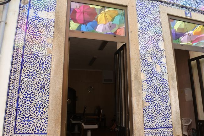　この建物は床屋さんで，中にレトロな椅子がありました。窓に映し出された傘もかわいいのですが，壁のアズレージョも見事でした。