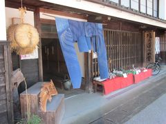 通りの向かいに藍染め暖簾が掛かったお店「塩の道づれ家」～、
当時の町屋（元明治中期の医院だそうです）を修復して郷土料理を食べさせるお店でした。
赤い毛氈に並べられた地元の柿や加工品がオブジェのようです。
まだ、早くて準備中でした。