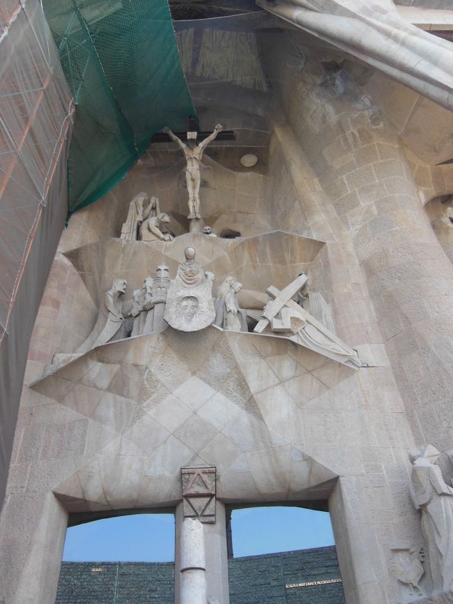 受難のファサードの彫刻は、ちょっと前衛的。<br /><br />左のカバーの奥は工事中ですが、中には描かれた数字の<br />縦・横・斜めの和が33になる魔方陣が隠れています。<br />イエスが処刑された歳を表しているのだそうです。