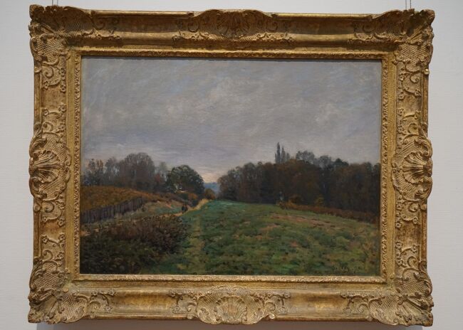 アルフレッド・シスレー「ルーヴシエンヌの風景」1873年<br />1871年、パリ・コミューンの間に、シスレーはパリの西方約30キロの地にある小村ルーヴシエンヌに移り住み、以後1874年夏からの4ヵ月にわたるイギリス旅行をはさんで、同年暮までルーヴシエンヌで過ごしています。本作品はその1873年にこの小村付近の風景を描いたもの。