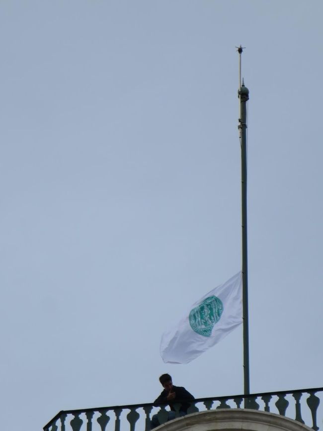 図書館を出てきたら、時計塔の上に人がいます。<br /><br />大学の教授が亡くなったそうで、弔う旗をあげていました。