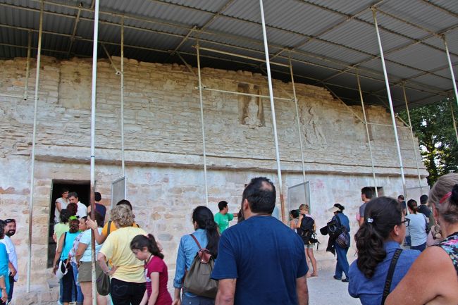 遺跡が閉まるまであと20分。<br />ボナンパック遺跡の次の見所は、壁画の神殿と呼ばれる入口が3つある小さな石造りの建築物だ。<br /><br />実は、この壁画の神殿の発見がボナンパック遺跡の発掘が行われるきっかけとなっている。<br /><br />壁画の神殿が発見されたのは今から半世紀ほど前の1946年。<br />雑誌ナショナル・ジオグラフィックのカメラマンであるジャイルズ・ヒーリー(米国人)がラカンドン族の映像を撮影しにジャングルに入った時に見つけたという。<br /><br />当時は今の遺跡の様に切り開かれた広場も無く、鬱蒼とした熱帯雨林のジャングルが広がっていた場所。<br />ガイドと共に鹿を追ってジャングルを撮影していたカメラマンの目の前に突如現れた巨大な階段ピラミッドと小さな石小屋。<br />興味を持って石の扉を押し開けたカメラマンの前に出現したのは、1000年前の壁画。<br />それも、それまで発見されたこともないほど鮮やかな色彩が保存されているマヤ文明の壁画。<br /><br />きっと、壁画を見つけたカメラマンさんは心臓が口まで飛び上るほど吃驚したと思うんだ…。<br />その時の感動を思うと、とても羨ましい。