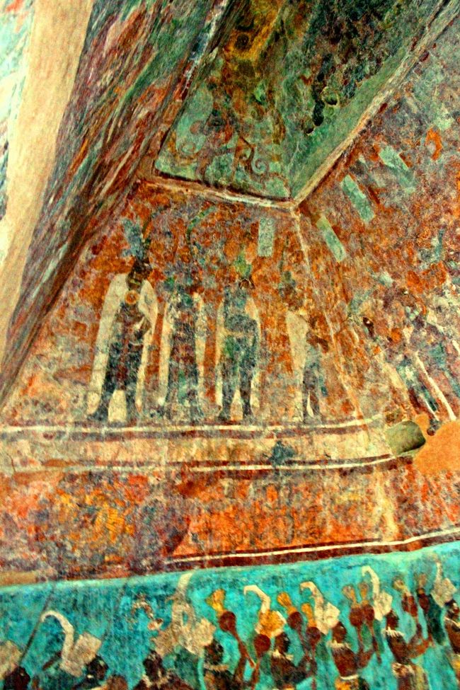 部屋の中は真っ暗で光源はない。<br /><br />だから最初は壁に描かれた絵も殆ど識別できないのだが、目が慣れてくると徐々にその色彩豊かな壁画が分かってくる。<br /><br />第一室は儀式の部屋と言われていて、出陣前の兵士を鼓舞する儀式、または石碑1で紹介したチャン・ムアーン二世王の後継者の披露儀式を表したものではないかと推測されている。<br /><br />天井までびっしりと描かれた色鮮やかな壁画。<br />下段の水色の背景の部分には楽隊の姿、2段目の朱色の背景のところには王族の姿、最上段にはマヤの神々の姿が描かれている。<br />