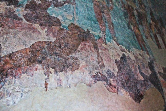 同室の壁画の別の場面では、脚を落とされて苦しむ捕虜(左)と両掌を上向きにして情けを乞う捕虜(右）の姿が描かれている。<br /><br />捕虜兵士たちのこの後の運命は、マヤの神々への生贄。<br />マヤ文明は、血の生贄を必要とする、言い換えれば生贄の為の人を生け捕りにするための戦争をするかなり好戦的な文明であったことが、この部屋の彩色壁画によって明らかになった。