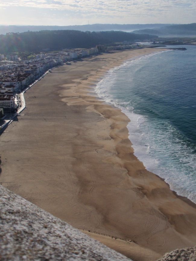 丘の上から眺めた海岸線。丘と海岸はケーブルカーで繋がっている。波打ち際に、波打つ砂紋が、波のように並んでる。左方は住宅街。