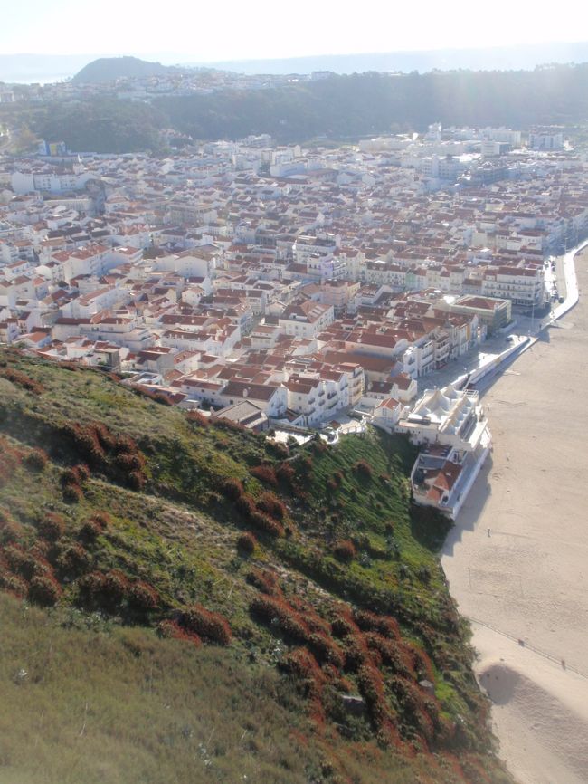海岸沿いに車道が走ってる。住宅街の色は、白壁とレンガ色の屋根。