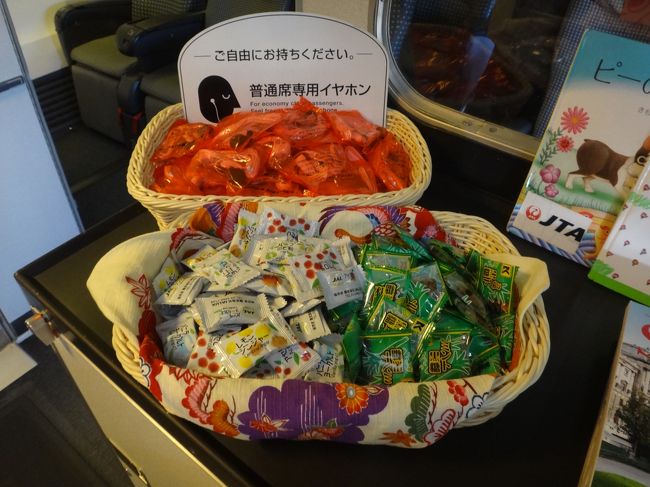 石垣島ー東京行きのJALの機内。<br /><br />機内のエントランス横に用意されていた普通席専用イヤホンと機内サービスの一種？<br />のJALのキャンディーなどの写真。<br /><br />往路と同様、JALのキャンディー（レモンジンジャー、アセロラ、アップル、<br />バニラヨーグルト、ハーブのど飴）の他、ミントの琉球黒糖が用意されていました。<br /><br />優先搭乗で機内に入った際に、往路のフライトとは異なるCAさんだったにも関わらず、<br />CAさんに「お帰りなさいませ。」と挨拶をされちゃいました (;^ω^)
