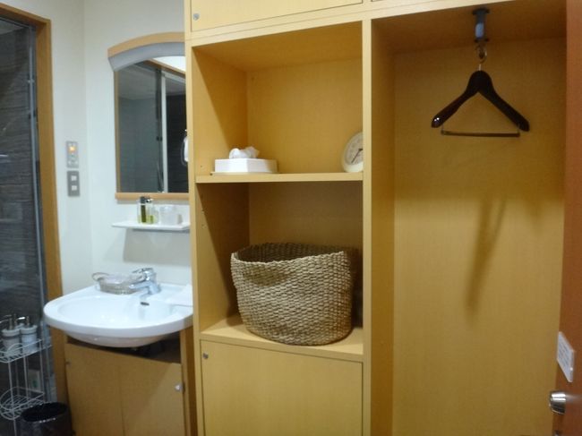 羽田空港国内線第1旅客ターミナルにあるクレジットカード会社ラウンジ<br />『エアポートラウンジ（中央）』のシャワールームの写真。<br /><br />ハンガー、テッシュボックス、脱衣用かごなどが用意されています。