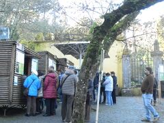 写真はペーナ宮殿への入場チケット販売窓口。

９時半前になると駅出て右の４３４のバス停に
観光客の列ができた。
バス停は出てすぐ右で左は４０３のロカ岬行き。

バス内では立っている人もいた。

バスはペーナ宮殿までの山道をくねくねと
蛇行しながら走った。
最初に王宮に停車した。
次に城壁後、その後にペーナ宮殿だった。
シーズンとは違うかもしれないが。

小さなバスがこの門の中に入って宮殿前まで
行ってくれるが乗らず坂道を歩いて行った。
疲れるので乗っても良いかもしれない。
入場のチケットを買う時に聞かれるが
断ってしまった。３ユーロで往復だった。

ペルーのマチュピチュまでの路線バスの道を
思い出す。
こちらはドル建てで運賃も高かった。
私たちは乗り放題の１５・５ユーロの
チケット購入してしたので安心だ。

シントラに９:５０頃に到着すると既に観光客５０人位が
大勢集まっていた。

観光バスや自家用車で来たのであろう。

開園直前にチケット売り場がオープンした。

チケット売り場は３ブースあって。
向かって右から順番に係りの人が来て
チケット販売をスタートする。

並んでいる人が少ないと思って一番左の
ブースに並ぶと係りの人はなかなか来ない。

結局最後まで待つことになるので要注意だ。

日本人観光客が並んでいたので少しお話しした。

一人はドイツで働いているという男性。
１泊で来て次はスペインに行くと言う。
右側に自動販売機もあるが王宮とセットのチケットなどは
有人の売り場でないとダメと言う。

ここからどこに行くか疲れ具合もあるし
明確に決めかねていたので
ここだけのチケットを購入した。
冬のシーズンは
６５歳以上９ユーロ
大人　　　１１．５ユーロ計２０・５ユーロを
クレジットで購入した。

もう一組は日本から来た若い女性の二人組。
彼女たちは間違えてムーアの城壁で降りてしまっていた。
それで歩いてここまできたとの事。
歩けると分かって見学の後も歩いて
ムーアの城壁に行くと言っていた。
ロカ岬は行かないと言う。
彼等とはその後も前後しながら良く出会った。。