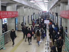 渋滞する道路を横目に、快調にひた走るエアポートエクスプレスに乗車して約25分。東直門（Dongzhimen）駅で地下鉄2号線に乗り換え、建国門（Jianguomen）駅＝写真＝で同1号線に再び乗り換えた。

2014年に高齢者が2億1千万人（高齢化率15.5％）に達した中国とはいえ、日本（同26％）と比べれば、地下鉄の車内を見渡すと圧倒的に若者の姿が多く、そのほとんどがスマホに夢中のようす。一時期、日本を訪れる中国人観光客のマナーの悪さが注目されたが、駅のホームでは、ボランティア（?）の人たちが、駆け込み乗車防止やゆずり合いなどのマナー向上を呼びかけるなど、中国人が”真の大国”の国民（人民）へ脱皮を図り模索する姿を垣間見たような気がした。