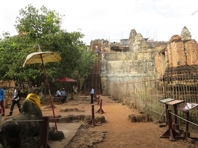 15：20頃に遺跡の下に到着した。<br /><br />「プノン・バケン」は丘上ピラミッド式のヒンズー教の寺院である。<br /><br />ここまでは人数制限はないが、この先は300人までの人数制限がある。<br />今はまだ入場者は少なく余裕で入場できた。<br /><br />遺跡の一部は工事中でクレーンが稼働している。
