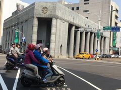林百貨の向かいの銀行（旧日本勧業銀行、現土地銀行）を撮ったつもりが、バイクの大人3人乗りが写っていました！
別の場所でママチャリならぬママバイクも見ました。ママの後ろに子供が二人。道路交通法違反ではないのだろうか。