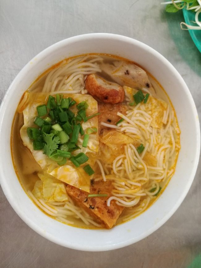 乙女心はまだ残っているものの、空腹には勝てない。この日のこころちゃんおすすめ料理はBun cha ca（ブンチャーカー）<br />地図で見るとダナン大聖堂近くだったので、<br />ドライバーには、ランチを済ませてもどると伝え歩き始めた。<br />ダナンはもうすっかり夏。少し歩くだけで、汗だく。地図とスマホのGPSを両手に<br />目当ての方向へいくも、なかなかお目当ての店は見つからない。<br />確かこの辺のはずなんだけど・・・・見つからない（涙）<br />でもここで妥協する５人ではなかった。とりあえず車に戻ろう。そして車で<br />連れて行ってもらおう。こんな時の結束力はすごい。<br />晴れて無事車で連れて行ってもらえて出会えた、ブンチャーカーのお店。<br />あまりきれいではないローカル店だけど、さすが雑誌に載っているだけのことはある。雑誌の写真を見せて、これ。と頼むと、歯のかけたおやじ、にやっと笑って<br />出してくれた。振り向くと、ほかにも日本人客が。<br />大枚はたいて、日本の雑誌に載せてもらったおかげで、大繁盛とほくそ笑んだのか、否かはわからないが、さつま揚げののった米粉の麺にたっぷりの別添え野菜を載せて、ライムをしぼって食べたブンチャーカ―は、ホロずっぱくてさわやかな、味だった。（写真は、パクチーを食べられないので野菜を載せる前の私の麺）<br /><br />