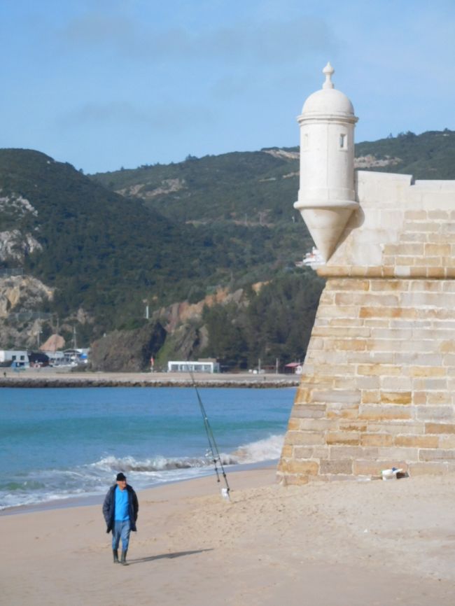 砦そばの海岸で魚釣りをする男性