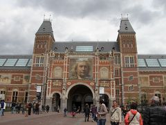 アムステルダム国立美術館に到着しました。美術館の向かい側の地下にある駐車場にバスを止めて観光開始です。
この美術館は２００３年に全面改装のため閉鎖され、１０年もの時を経て２０１３年４月に再オープンしました。
ところで「みんなのアムステルダム国立美術館へ」という映画が上映されたのをご存知でしょうか？
２０１４年１２月から公開され私は２０１５年の春にこの映画を見ました。
見る前はアクステルダム国立美術館の収蔵品を紹介した美術映画だと思っていましたが、内容は国立美術館の改修工事のドキュメンタリー映画でした。
美術館の改修工事は途中で大きな問題が発生して中断を繰り返して、遅れに遅れて当初２００８年にオープンの予定が大きく伸びてしまいました。
この映画はどうして再オープンまで10年もの年月がかかってしまったのかをテーマとした映画です。
館長や学芸員の苦悩、市民や建築家との対立、揉めに揉め怒りがぶつかり合うスタッフたち、その中でも美術スタッフの作品に対する愛情や良いものを造ろうとする熱意や熱い思いが描かれていました。