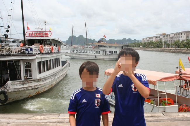 グロッキー寸前、約４時間でハーバーに到着。<br />台風の影響でまだ雲は厚かったが、<br />雲の間からの日差しはじりじりとしていた。<br />ここからボートで客船に移動。<br /><br />さて、息子二人が着ているのは、サッカー日本代表のユニフォームのレプリカ。<br />この年、２０１４年　ブラジルでＷＣが開催された時のデザイン。<br /><br />そのちょっと前の５月の事。<br />南シナ海のベトナムが主張する排他的経済水域に、違法設置した中国海洋石油総公司の石油掘削リグをめぐり、ベトナムと中国の艦船の衝突が相次いだことにより、発生した反中デモ。<br /><br />結局、在ベトナム中国人１８人を含む約２０人も死亡した。<br />また、在日本企業も被害にあった。<br /><br />「マジかー！」<br />このままでは、旅行は中止か？と心配したものの、２週間程度で収束して、一安心。<br /><br />でも、ベトナム人からみたら、中国人も日本人も一見ではわからないだろう。<br />旅行の間、勘違いされて嫌がらせを受けたら、嫌だなっと思った私が考えた。<br /><br />「Ｗｅ ａｒｅ Ｊａｐａｎｅｓｅ！」<br />のアピ、アピ。<br /><br />ベトナムではサッカーが人気スポーツなのもあって、<br />現地でおおむね好評だったよ。