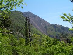 登山道の途中から眺めた平成新山。今は活動を停止しているため穏やかな山です。噴煙は見えません。もう噴煙は上がってないのかな？
登山道を進んで行くと普賢岳と国見岳方面の分岐（紅葉茶屋）にさしかかります。
ここから途中鎖場もある急な登りが続きます。登山道は岩場を直登する感じでかなり険しい道でした。途中何度も休憩しながら着いたと思ったら、まだ山頂は上のほう。
何か廃墟のようなものがありました。石の柱は途中から折れてあちこちに散らばっていました。
実はこれは山頂の下に建てられていた普賢神社の石の鳥居なんです。社殿は燃えて跡形もありません。ただ鳥居の残骸と、鳥居の根本部分のみが廃墟のように残っていました。
普賢岳の火砕流や溶岩に焼かれ、火山岩に打ち砕かれたのでしょう。
その被害の跡を見ると言葉もありませんでした。
