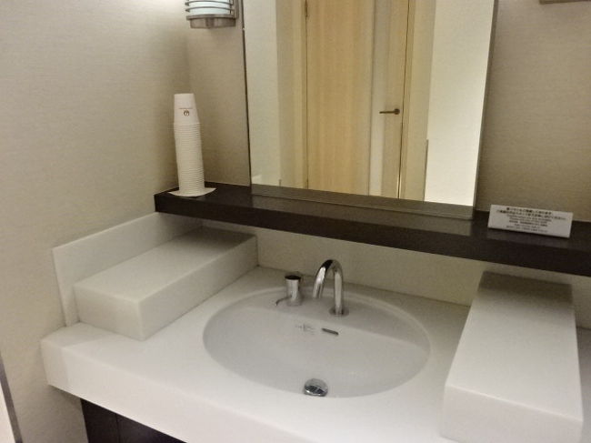 洗面台の左奥には、ＪＡＬ鶴丸マークの紙コップが。エコノミー席で飲み物入れるコップと一緒かも(笑)