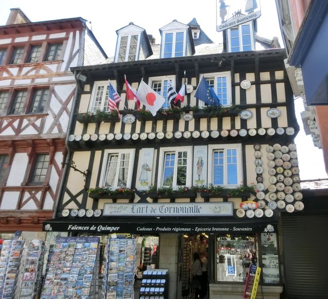 広場にはカンペール特産カンペール焼の土産物店アール・ド・コルヌアイユ。<br />EUやアメリカの旗に交じって日の丸の旗が。