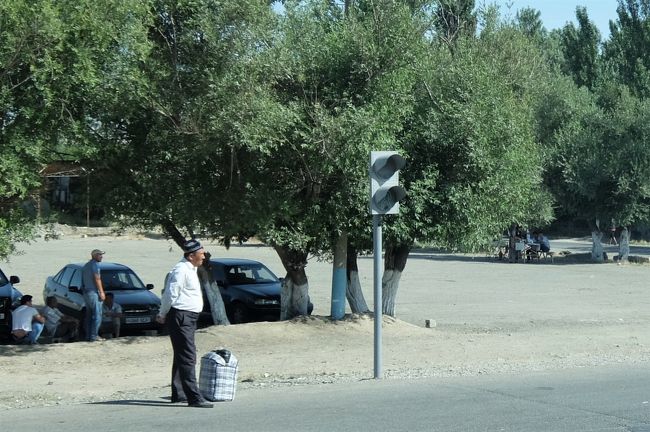 ヒッチハイクか乗り合いタクシーを待っているおじさん。