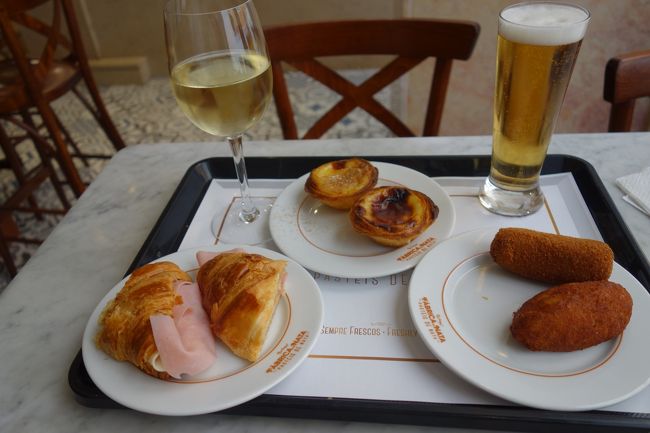 そしてポルトガルで最初の注文です。<br />カウンターで指さしです。<br />パステル・デ・ナタ1ユーロ×2個、ミートクロケット1.3、パステル・バカリャウ1.3ユーロ、クロワッサンミスト2.2ユーロ、白ワイン1.75ユーロ、生ビール1.3ユーロ計9.85ユーロ。<br />うーん、アルコールが安いですね。<br /><br />実はここでの食事が私はポルトガルナンバーワンでした。<br />ナタはもちろん美味しいですが、ここのコロッケ類はタラもお肉もみっしり入っているのに臭みや塩辛さが全くなく美味しい。<br />クロワッサンもすごくおいしいし、何よりポルトガルでは何も言わなくても半分に切ってくれるんですよね。<br /><br />お店のお姉さんもすごく優しい感じでした。
