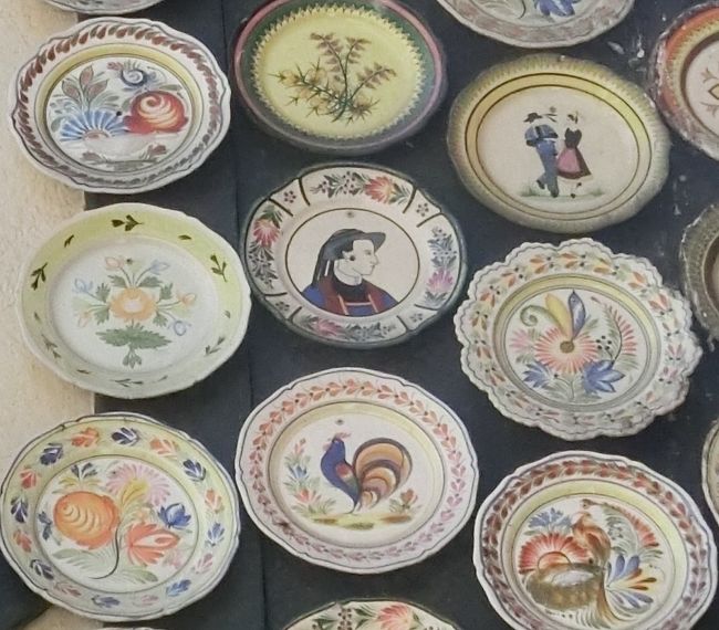 カンペール焼の起源は１５世紀頃で、当初は素焼きのものだったが、１８世紀初めに名工が出たのと王家の援助があり高級な陶器になっていく。<br />絵付けはすべて手描きでブルターニュの民族衣装の男女、花、鳥などの図柄が多い。