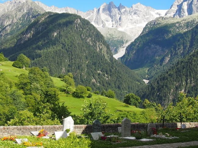 部屋からこの景色が見えます。目の前にある村の教会の墓地です。花が一杯で日本のお墓とは雰囲気が違います。後ろの山はPiz.Badile（3311ｍ）