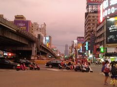 17:50　高雄駅
スクーターは信号待ちで最前列へ。一回で10台くらいはザラに見ます。
奥に高雄85ビルが見えます。