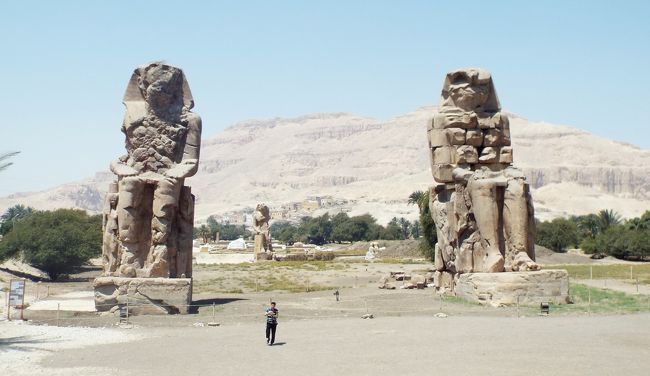 　さて、いよいよ世界遺産【ルクソール西岸観光】に行って来ます!!最初にメムノンの巨像見学です!!離れて見ると、人がこんなん小さく見えます!!<br /><br />　メムノンの巨像＝エジプト・ルクソールのナイル川西岸にある2体のアメンホテプ3世の像です。呼び名はギリシアの伝説、トロイ戦争に登場するエチオピア王メムノーンに由来します。高さ18ｍもあります。