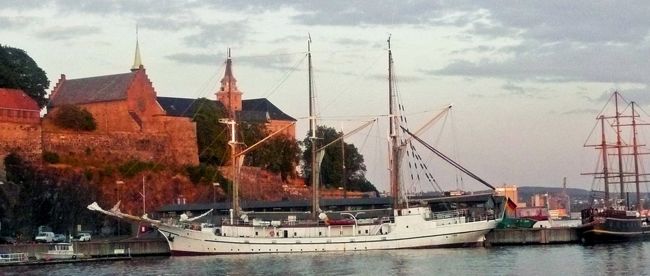 港に沿って左側に目をやると、夕日で朱色に染まったアーケフシュース城をバックにした、<br />繋留中の純白の帆船のコントラストが際立つ。